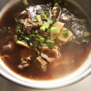 bowl of lamb, ginger and longan soup, with green onions on top. Chinese medicinal food for winter.