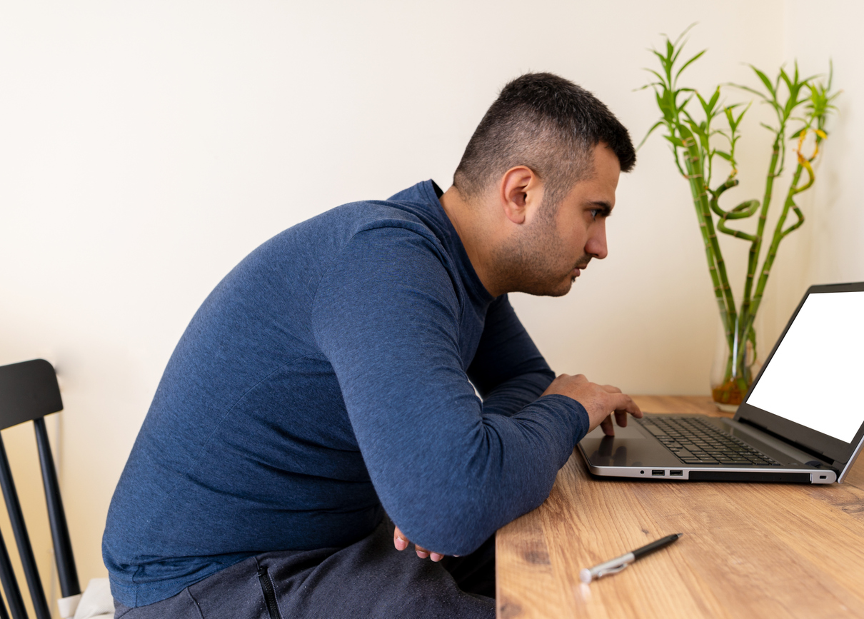 man with hunched back and forward neck posture sitting at a computer